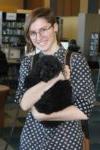 smiling female student holding small black dog